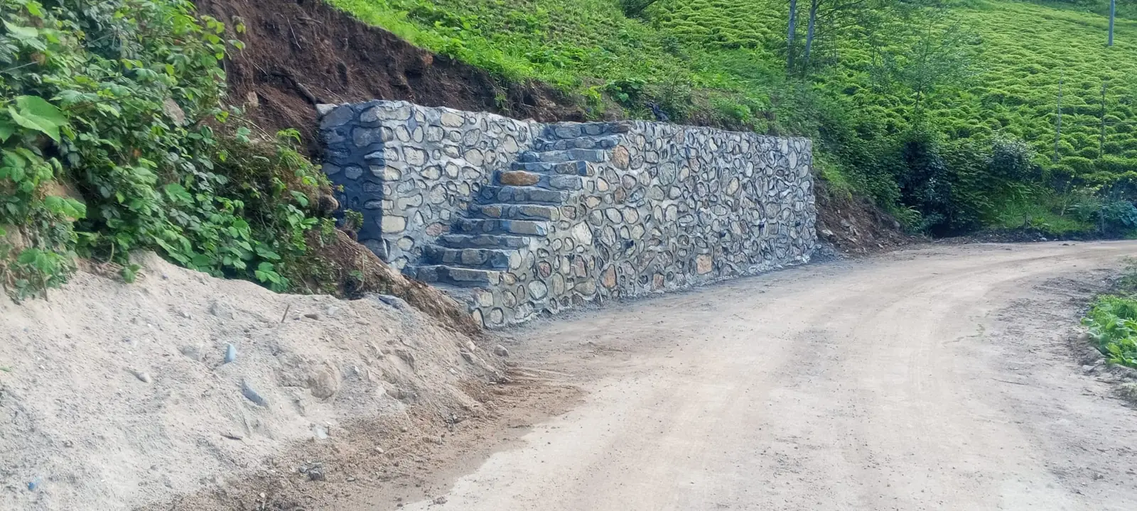 Yol kenarında tamamlanan taş duvar ve taş merdiven